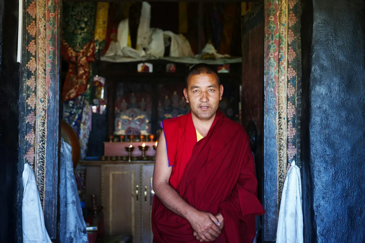 A Buddhist monk standing in the doorway of a mountain monastery